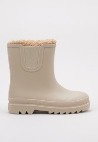 Beige gumová botka s texturovanou podrážkou, měkkou kožešinovou podšívkou nahoře a zaobleným designem. Obsahuje zesílenou část kolem kotníku.