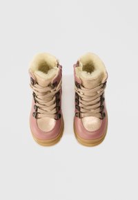 Ροζ και χρυσές χειμερινές μπότες παιδιού με μπεζ κορδόνια, μεταλλικές οπές και αφράτη κρέμ φούστα εσωτερικά.
