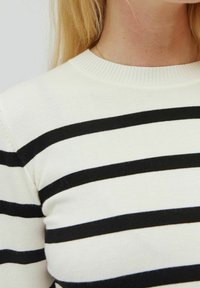 Sweter w paski w kolorze kremowym z czarnymi, poziomymi paskami. Posiada prążkowany, okrągły dekolt i fakturowany materiał dziany.