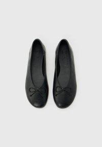 Ζευγάρι μαύρα μπαλαρίνες με μικρά διακοσμητικά φιόγκους στο μπροστινό μέρος, εμφανιζόμενα από πάνω σε ανοιχτό φόντο.