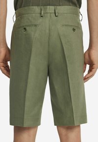 Grüne Leinen-Shorts verfügen über ein maßgeschneidertes Design mit Falten, seitlichen und hinteren Taschen mit Knopfverschluss sowie einem geraden Schnitt. Der Stoff hat eine glatte Oberfläche.