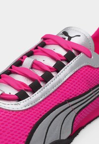 Κοντινή λήψη ενός ροζ αθλητικού παπουτσιού με ασημί γλώσσα, μαύρες τρύπες για κορδόνια και νέον ροζ κορδόνια, με το λογότυπο της Puma στη γλώσσα.