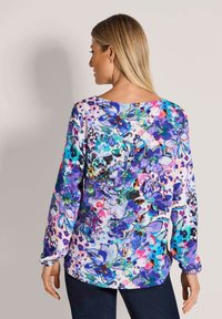Langärmeliges Oberteil aus leichtem Stoff mit lebendigem Blumenmuster in lila, blau und grün; Rundhalsausschnitt und lockere Passform.