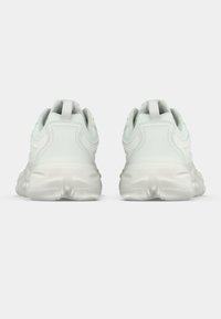 Ανοιχτό πράσινο αθλητικό παπούτσι με υφασμάτινο επάνω μέρος με υφή και μαλακή λευκή σόλα. Διαθέτει θηλιά στο πίσω μέρος για εύκολο φόρεμα. Στρογγυλεμένος σχεδιασμός.