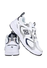 Zapatillas deportivas blancas que combinan materiales de malla y sintéticos. Acabados en gris y navy, con un collar acolchado y una suela de goma texturizada.