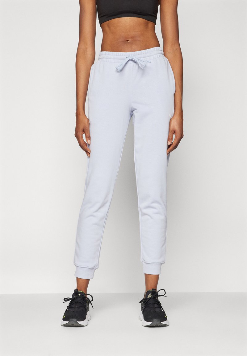 Hellblaue Sweatpants mit Zugbandbund, gerippten Bündchen und Seitentaschen, kombiniert mit schwarzen Sportschuhen. Weiche, glatte Textur.