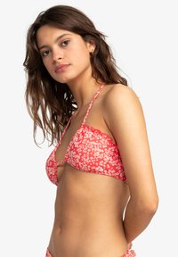 Červený kvetinový bikiny top s trojuholníkovými pohármi, ramienkami a výrezom v tvare kľúča; obsahuje biely kvetinový vzor na jemnom materiáli.