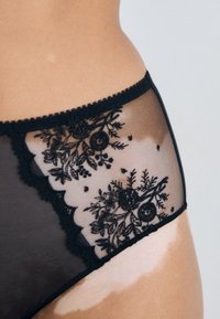 Schwarze Spitzenunterwäsche mit hohem Bund, floralem Stickerei, durchscheinendem Mesh, gewellten Kanten und einem dekorativen Bundmuster.