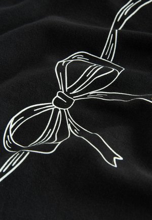 Material negru cu o margine albă a unei funde legate în centru, evidențiind textură fină și detalii ale unei panglici fluidă.