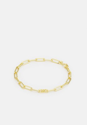 Gold-tone metal bracelet featuring elongated links and a central logo tag. Smooth texture with a polished finish. Secure clasp closure.