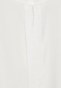 Witte blouse met een textuurstof en een subtiel stippenpatroon, een sleutelgatopening aan de achterkant en een gladde halslijn.