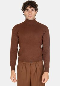 Maglione a collo alto marrone, design aderente, texture a coste, maniche lunghe, realizzato in un materiale morbido, abbinato a pantaloni marroni.