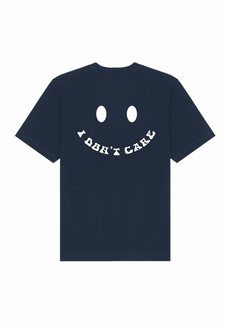 T-shirt en coton bleu marine à manches courtes, avec un grand design de visage souriant blanc au dos et le texte "JE M'EN FOUS" en dessous.