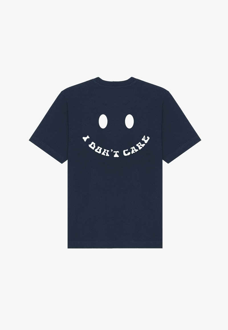 T-shirt in cotone blu navy con maniche corte, presenta un grande disegno di faccina sorridente bianca sul retro con il testo "NON MI INTERESSA" sotto di esso.