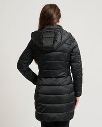 Chaqueta negra acolchada con capucha, con textura acolchada y costuras verticales, de longitud hasta la rodilla y corte ajustado. Sin herrajes ni detalles visibles.