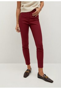 Burgundské slim fit kalhoty vyrobené z hladké látky, s vysokým pasem a zakončením nad kotníky, v kombinaci s tmavými polobotkami a světlým svetr.