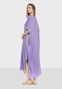 Lång lila kaftan med sidofrackar, med ett mönstrat kant på ärmarna. Tillverkad av lättviktig tyg, med en slät textur.