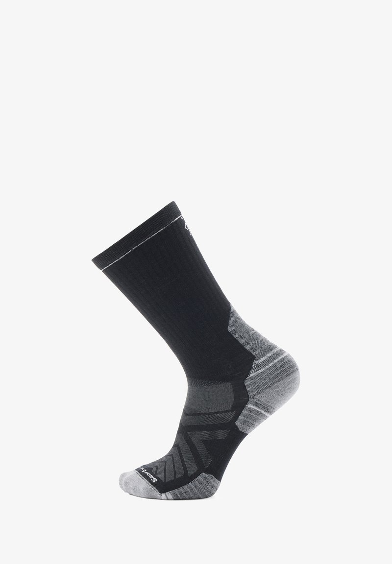 Calcetín deportivo negro y gris con parte superior acanalada, talón reforzado y patrón en zigzag en la punta. Fabricado con material transpirable.