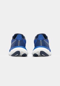 Blue athletic shoes with a smooth fabric upper, textured accents, and a white cushioned sole. Features a heel tab and striped design on the upper.