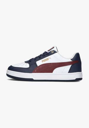Witte sneaker met marineblauwe en bordeaux accenten, gemaakt van leer. Bevat een gestructureerd oppervlak, perforaties op de teen en gouden logo-details.