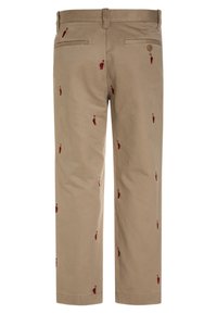 Beige housut, joissa on maroon-värisiä brodeerattuja kuvioita, kaksi takataskua, joista toisessa on napin suljenta, suorat lahkeet.