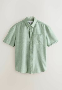 Chemise vert clair à manches courtes avec petit motif à carreaux et poche poitrine, posée à plat sur une surface blanche.