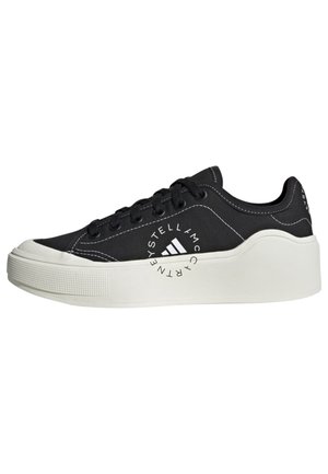 Zwarte lage sneaker met dikke witte plateauzool, zwarte veters, witte stiksels en een rond logo aan de zijkant met de tekst "Stella McCartney."
