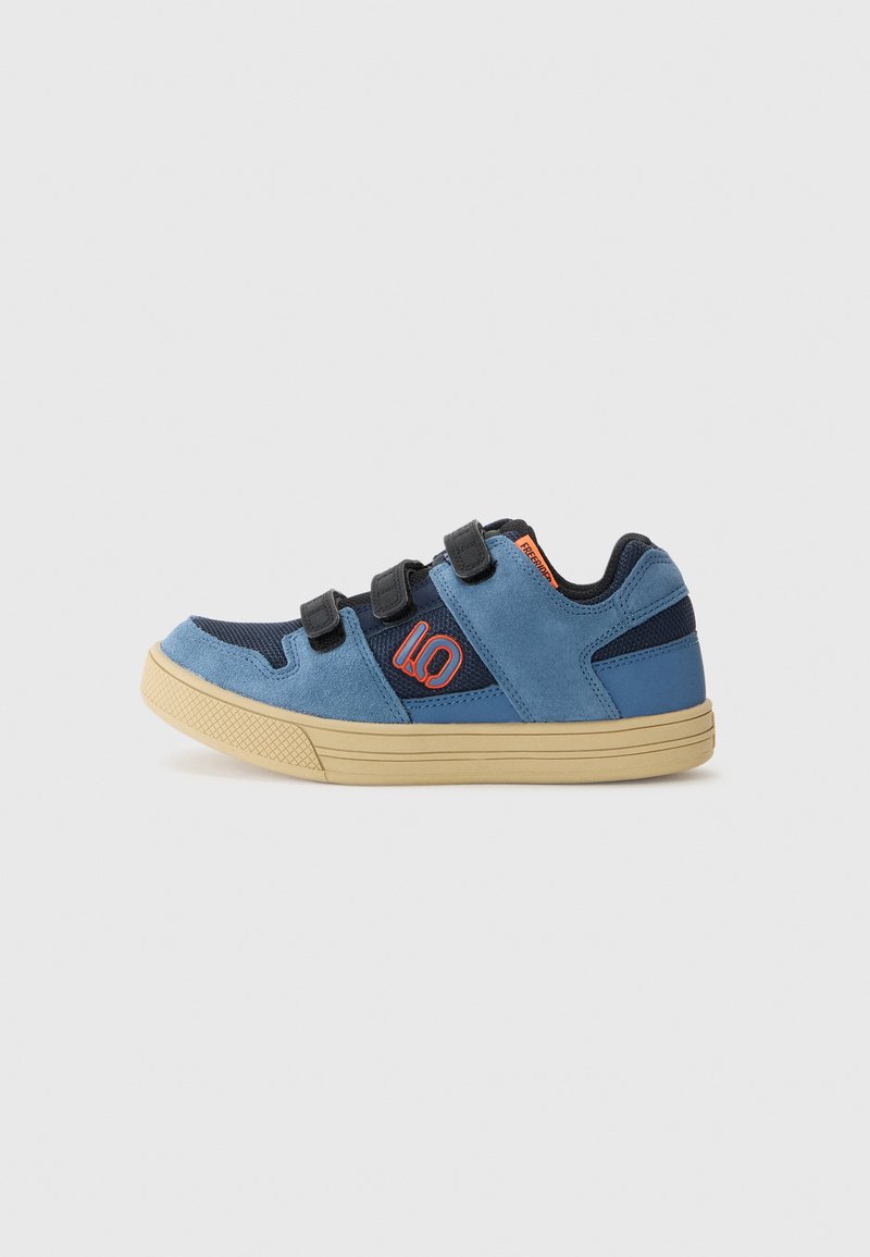 Modri semiš in mrežasti športni copat z Velcro trakovi, teksturirano gumijasto podplat in oranžno logotipno podrobnost na strani. Nizkoprofilna zasnova.
