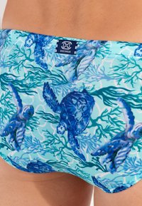 Herren-Badehosen in Hellblau mit einem Muster aus Schildkröten und Seegras. Hergestellt aus weichem Stoff mit bequemer Passform und gesticktem Logodetail.