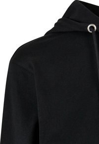 Sweat à capuche noir avec cordon de serrage et œillet en métal sur le devant, près de l'encolure, montrant l'épaule gauche et le haut de la poitrine.