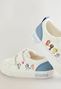 Witte sneakers met blauwe accenten, voorzien van illustraties van cartoonfiguren en klittenbandsluitingen. Rubberen zool; gladde textuur.