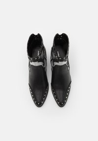 Czarne skórzane botki za kostkę z ostrymi czubkami, srebrnymi ćwiekami wzdłuż krawędzi oraz dekoracyjnym wzorem na mankiecie.