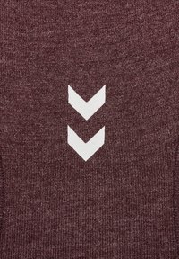 Vinröd stickad tyg med två vita vinkelformade mönster placerade vertikalt på ytan. Texturen ser slät ut med en något melerad look.