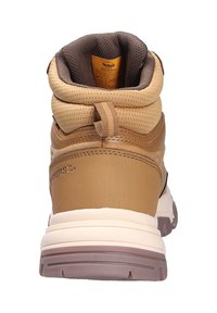 Tan wandelschoenen met een gewatteerde bruine kraag, gestructureerde materialen en een stevige crème en bruine rubberen zool. Merkinformatie zichtbaar aan de zijkant.