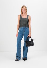 Grauer gerippter Tank-Top, hoch taillierte blaue Jeans und eine kleine schwarze, strukturierte Handtasche. Das Model trägt spitze schwarze Ballerinas.