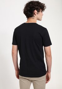 Černé tričko s krátkým rukávem vyrobené z měkké bavlny. Má klasický kulatý výstřih a slim fit. Látka se zdá hladká, bez viditelných vzorů.
