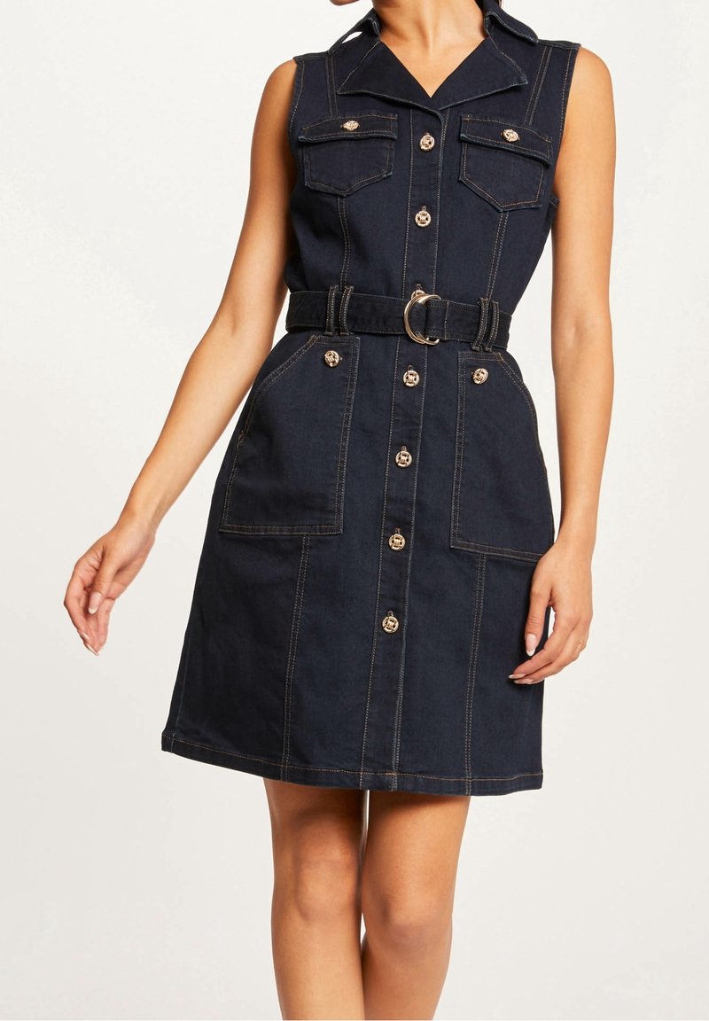 Robe sans manches en denim foncé avec patte de boutonnage, deux poches poitrine et taille ceinturée. Coutures contrastées et boutons dorés.