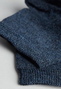 Strikket stof i forskellige nuancer af mørkeblåt, med en blød tekstur og et nærbillede af det intrikate væv og de færdige kanter.