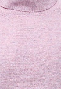 Tissu tricoté rose doux avec un col roulé côtelé plié sur un pull ou un chandail.
