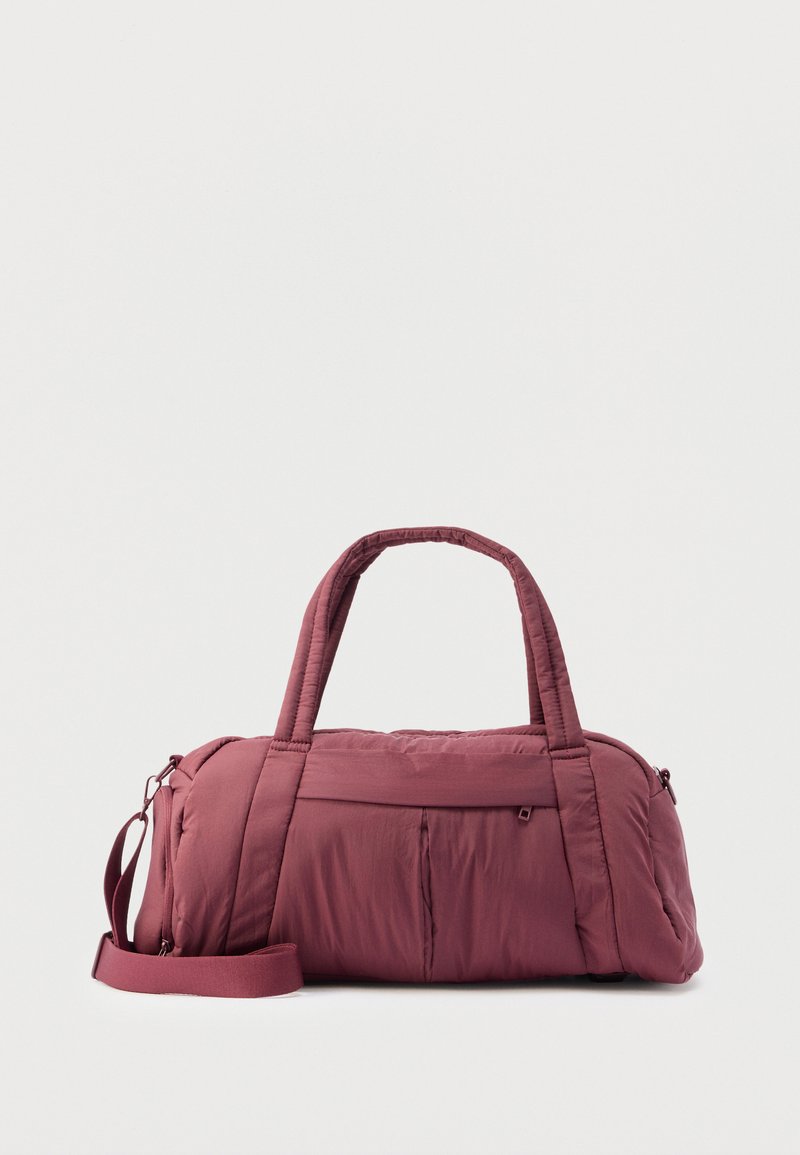 Μπορντό σακβούαγια από απαλό, καπιτονέ ύφασμα. Διαθέτει διπλές χειρολαβές, αφαιρούμενο ιμάντα ώμου και τσέπη με φερμουάρ στο μπροστινό μέρος.