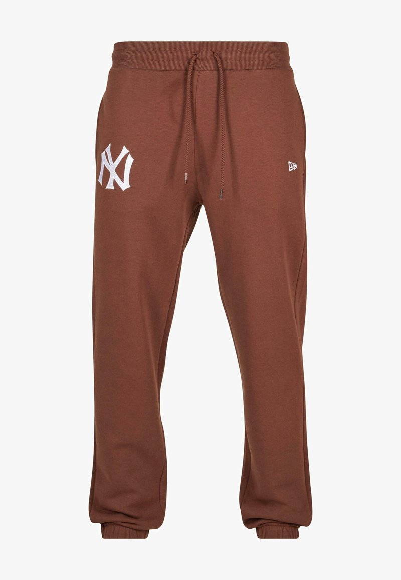 Brūnas sporta bikses ar elastīgu jostasvietu, regulējamu auklu un baltu izšūtu logo kreisajā augšstilbā. Mīksts kokvilnas maisījuma materiāls.