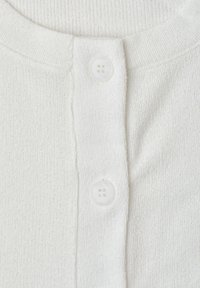 Close-up van een witte gebreide stof met twee witte viergaatjes knopen op een knopenstrook.