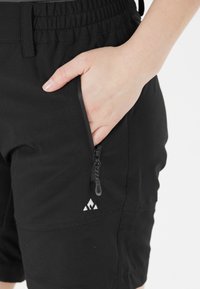Svarta shorts med elastisk midja, med en ficka på sidan med dragkedja och en liten vit logotypdesign nära fållen.