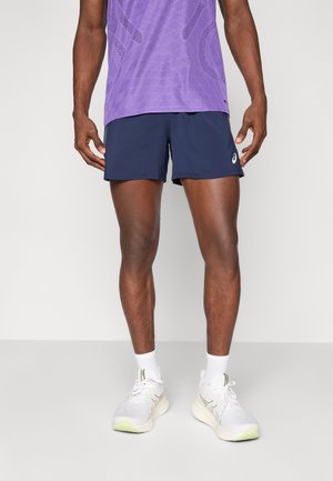 Men's purple patterned athletic shirt, navy shorts, white sneakers with green accents, and white socks. Athletic fit and smooth texture.