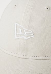 Weißer Baseball-Cap aus strukturiertem Baumwollstoff, mit einem erhabenen weißen gestickten Logo auf der Vorderseite. Glatter, gebogener Schirm und Nähdetails.