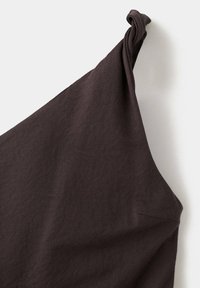Tissu marron foncé avec un détail de sangle nouée, présenté sur un fond clair uni.