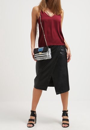 Burgundy satin camisole with thin straps, paired with a black faux leather wrap skirt. Accessorized with a black and white textured handbag.