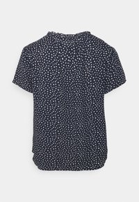 Blusa blu navy a maniche corte con motivi bianchi sparsi, con scollatura tonda e dettagli plissettati sul retro.