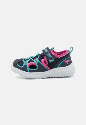 Navy blue and pink children's sneaker with white sole, teal accents, ventilation cutouts, and adjustable Velcro strap.