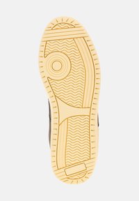 Sole di una sneaker, materiale in gomma, colore beige chiaro, pattern testurizzati con linee ondulate e dettagli circolari, design resistente per una buona aderenza.